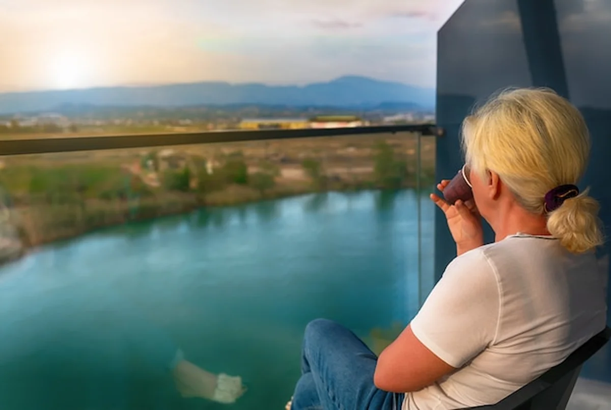 Kobieta pije kawę na balkonie o wschodzie słońca