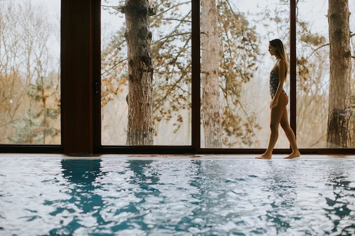 Młoda kobieta przy oknie nad krytym basenem w spa