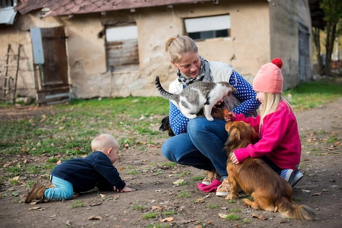 Szczęśliwa rodzina uściskująca i karmiąca psy, koty i kozy na farmie